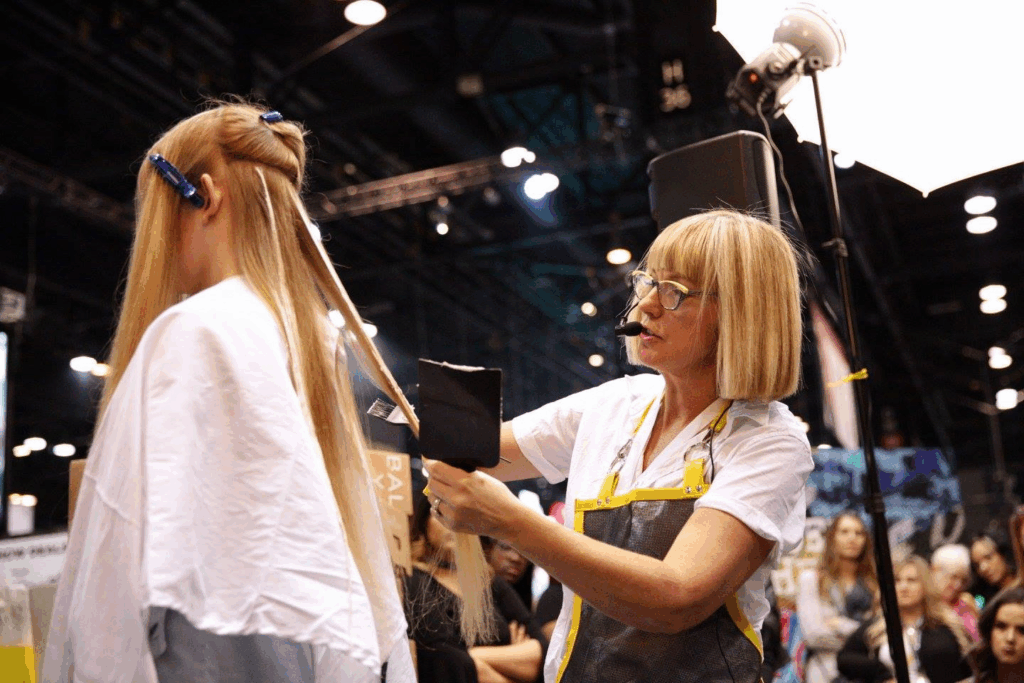 A woman demonstrating a hair highlighting technique at America's Beauty Show