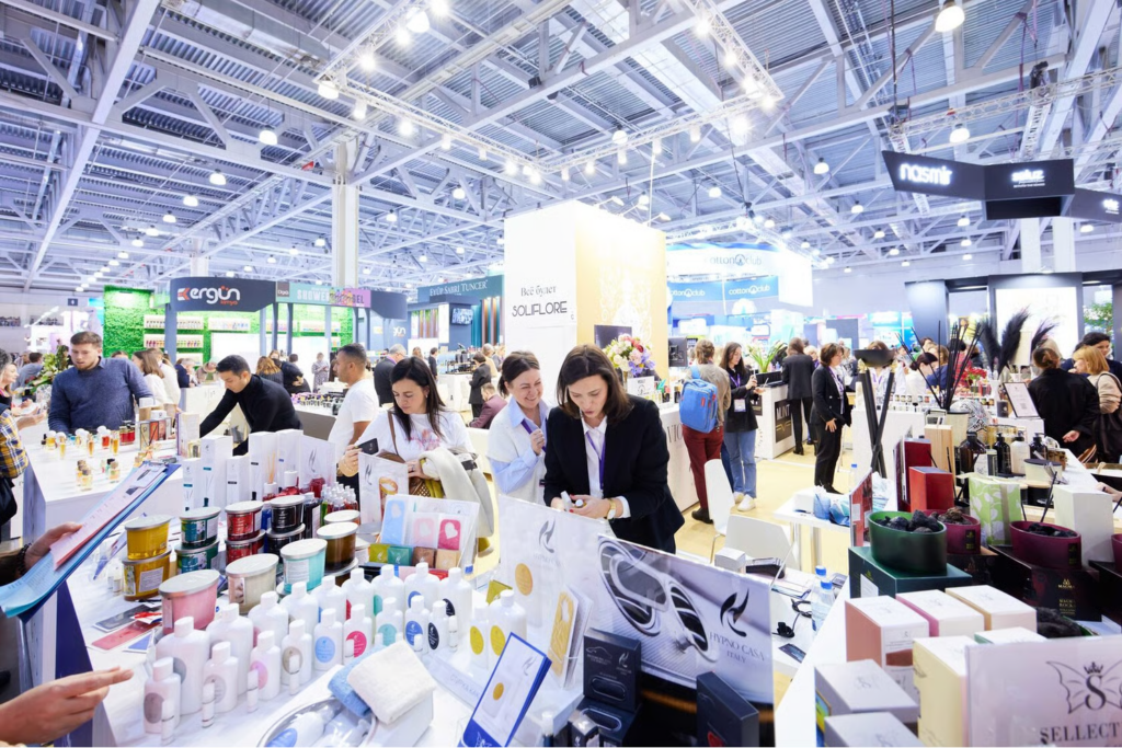 Crowded beauty trade show floor of InterCHARM Moscow with exhibitor booths, product displays, and attendees browsing