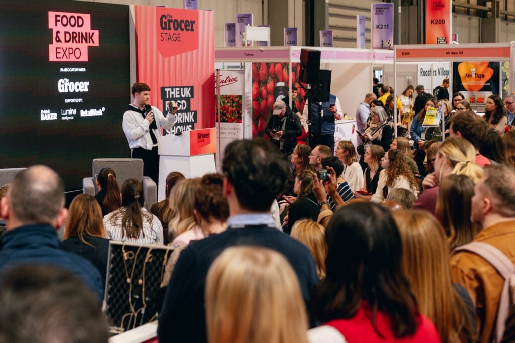Crowd gathered around a speaker presentation at the Food & Drink Expo trade show floor.